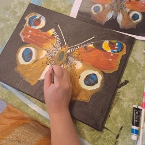 Opiskelija maalaa kuvaa perhosesta.