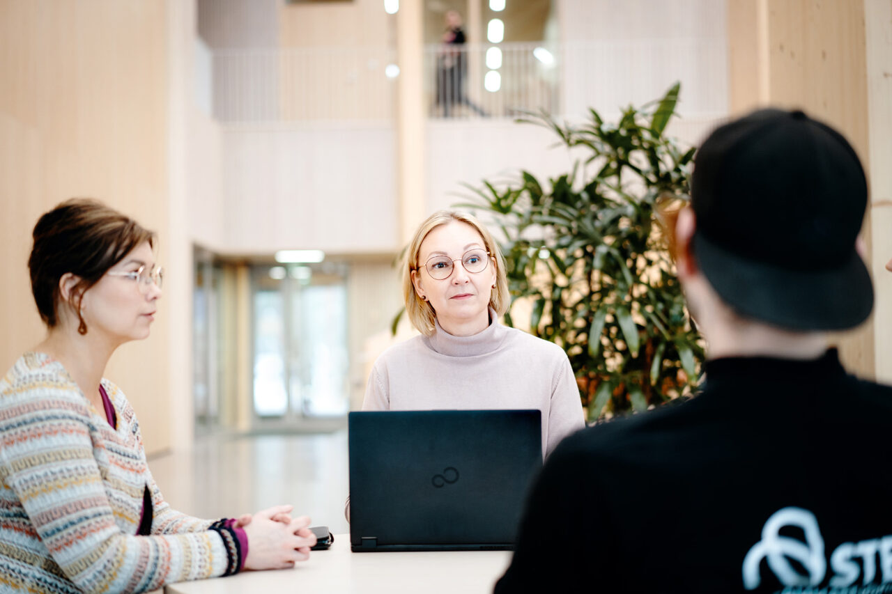 Opiskelija keskustelee opinto-ohjaajan ja opintosihteerin kanssa.