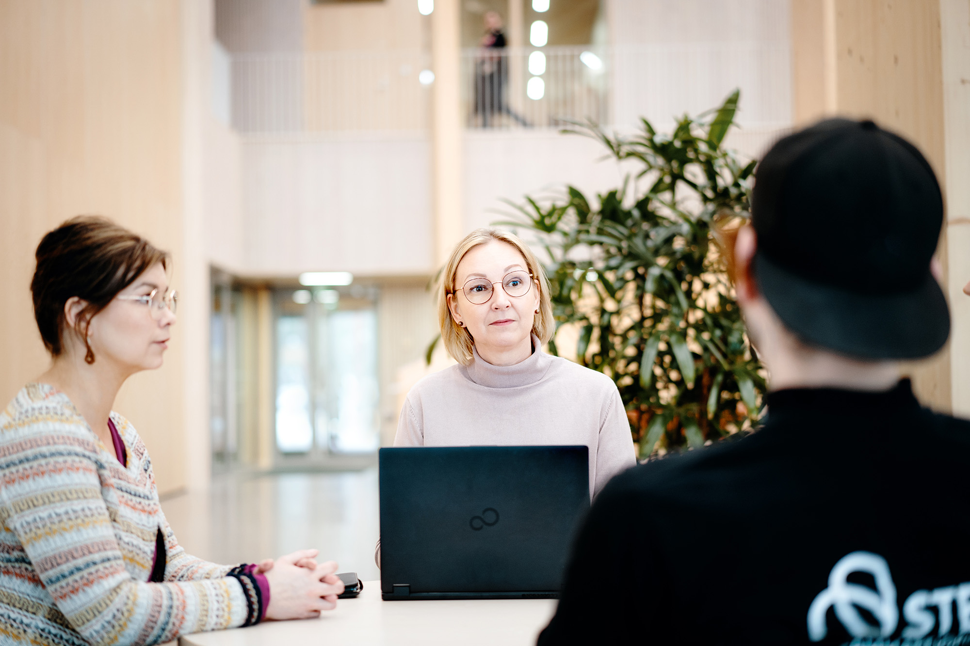 Opiskelija keskustelee opinto-ohjaajan ja opintosihteerin kanssa.