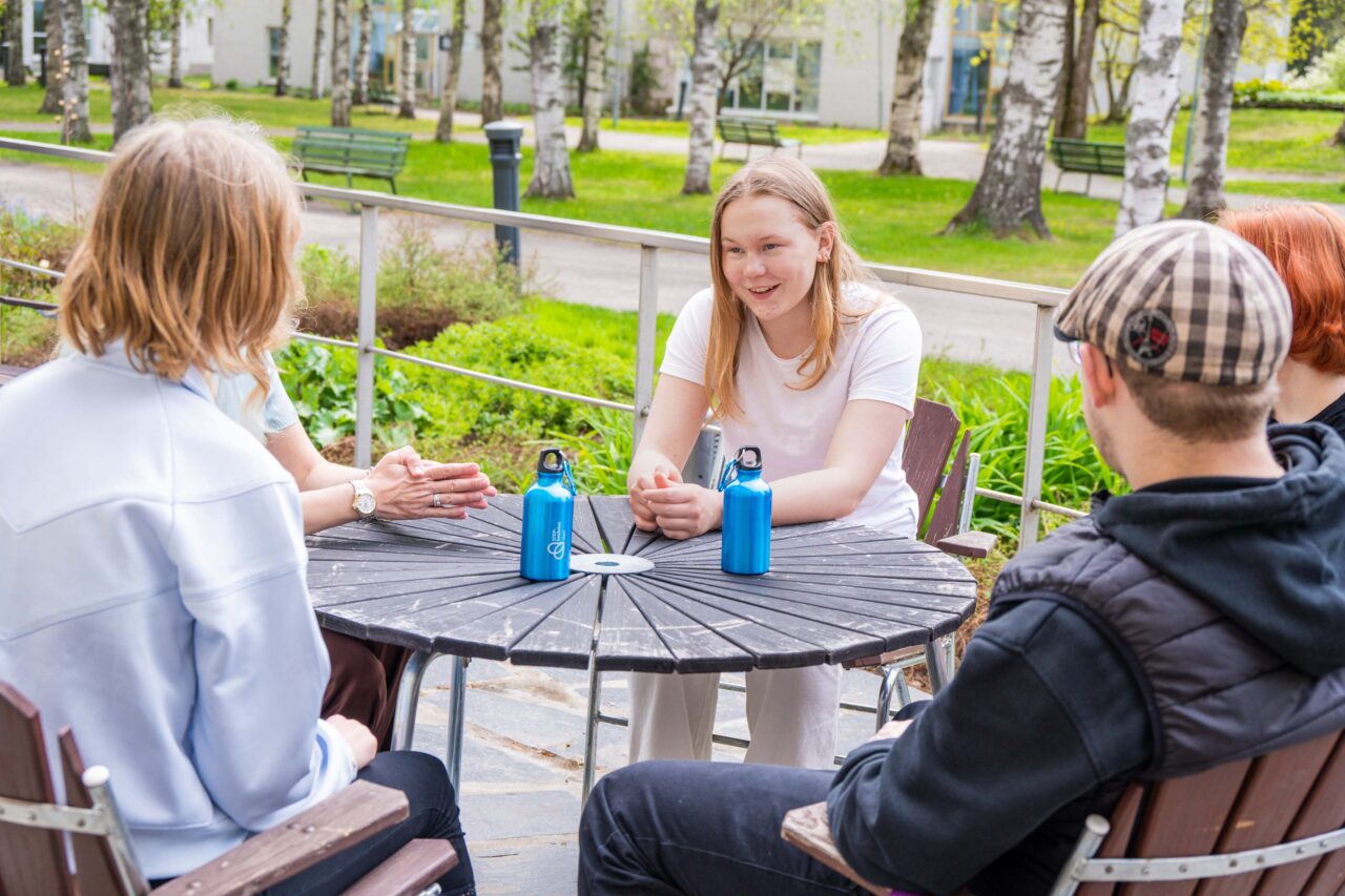 Opiskelijoita tauolla kampuksen opiskelijaravintolan terassilla.