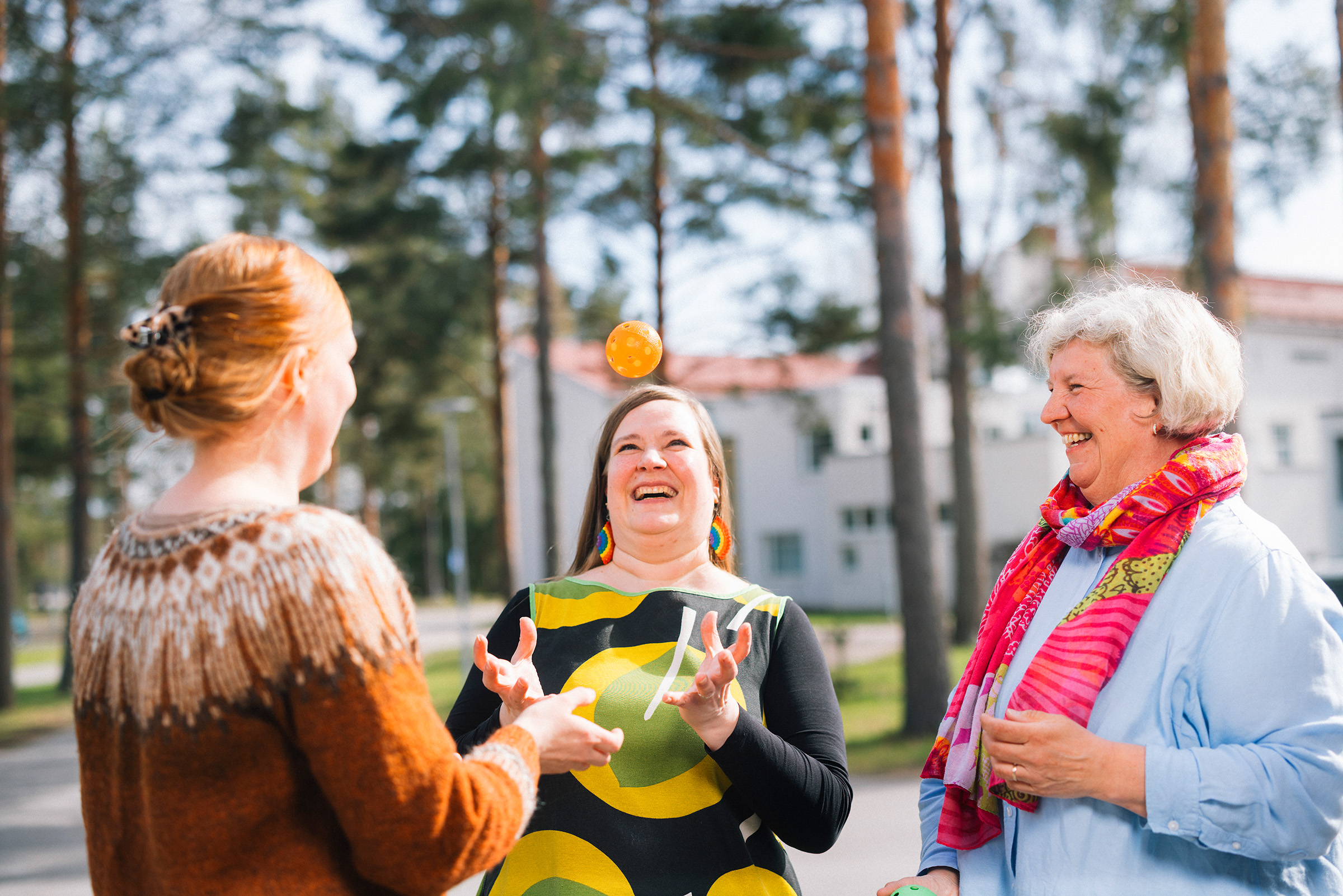 Kouluttajat ja kurssilainen nauravat ja heittävät palloa