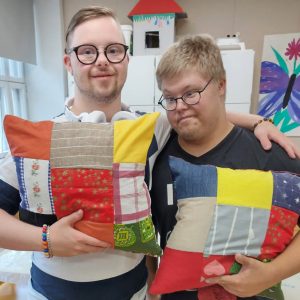 Kaksi STEP-kansanopiston Ruokolahden kampuksen Aino ja Oiva koulutuksen opiskelijaa esittelevät ompelemiaan tyynynpäällisiä.