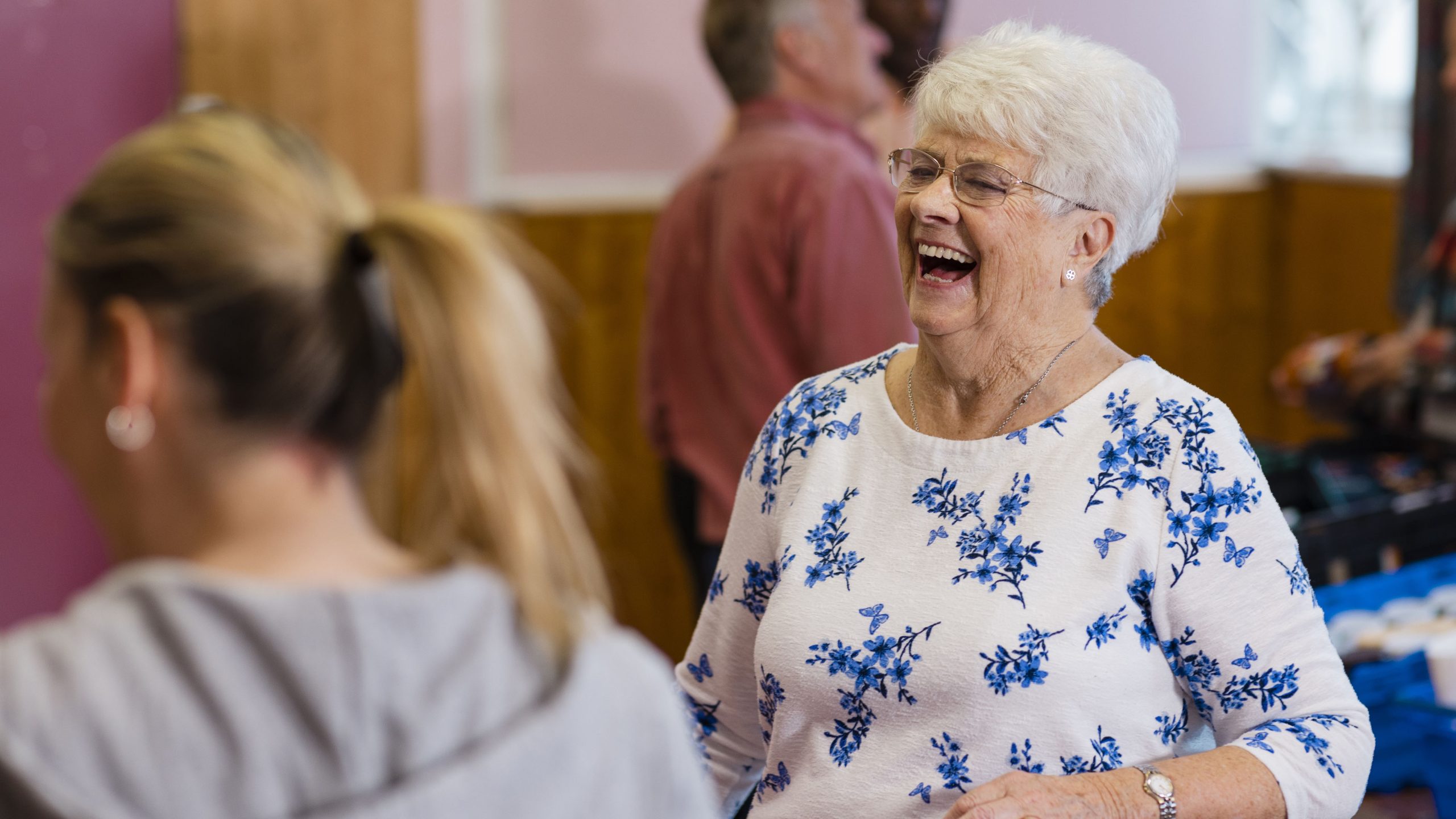 Seniorinainen nauraa iloisena ikäihmisten tapahtumassa.