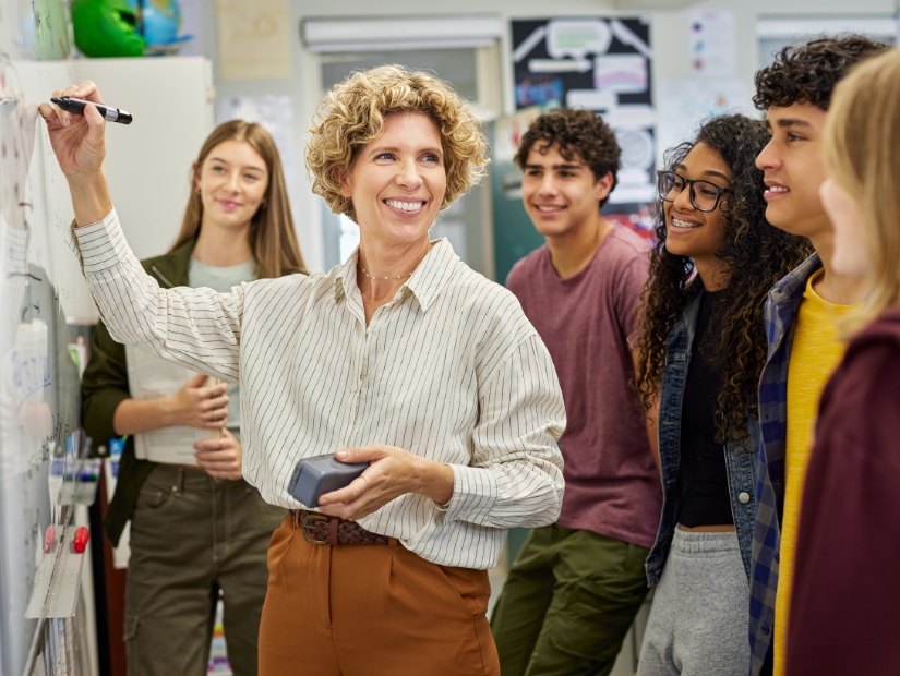 Opettaja ja lukio-opiskelijat opetustilanteessa.