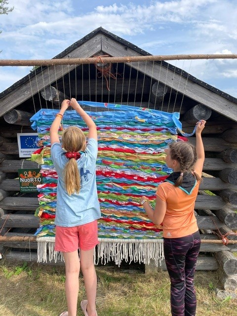 opsikelijat kutomassa mattoa
